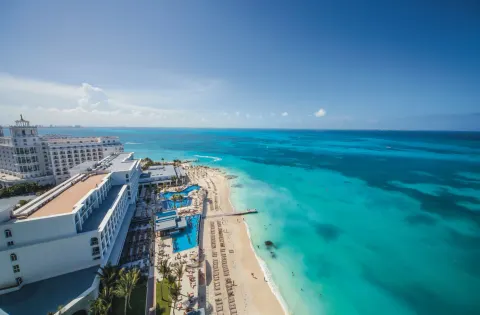 Aerial view of the beach, pools, and turquoise shoreline at Hotel Riu Cancun.