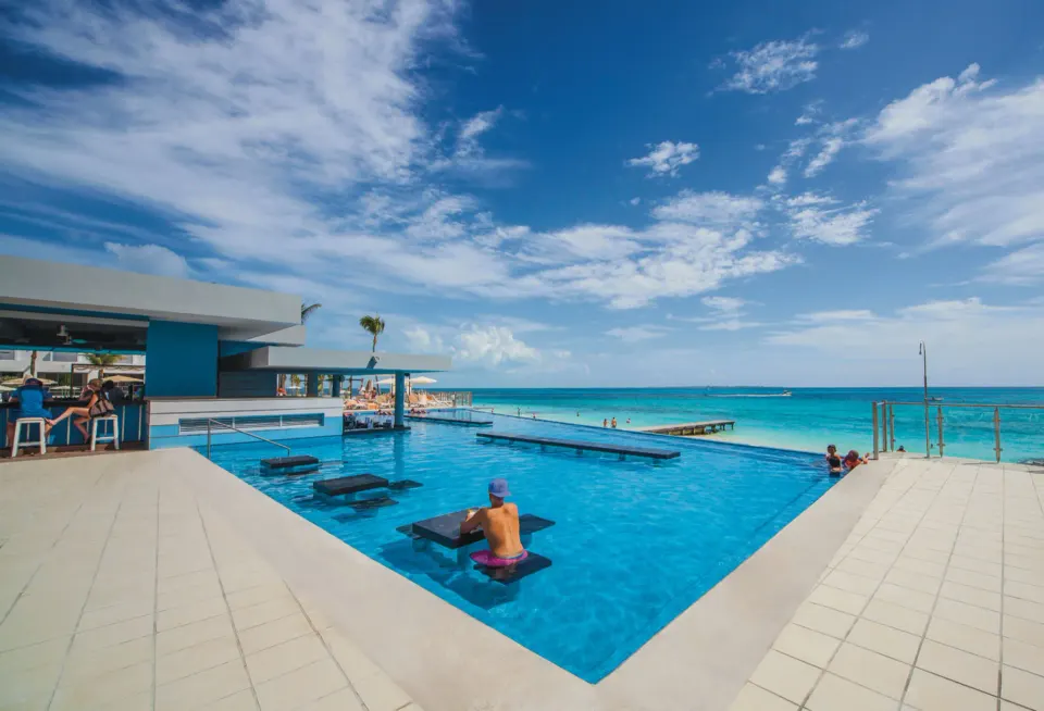 Infinity pool with swim-up bar and Caribbean Sea at Hotel Riu Cancun.