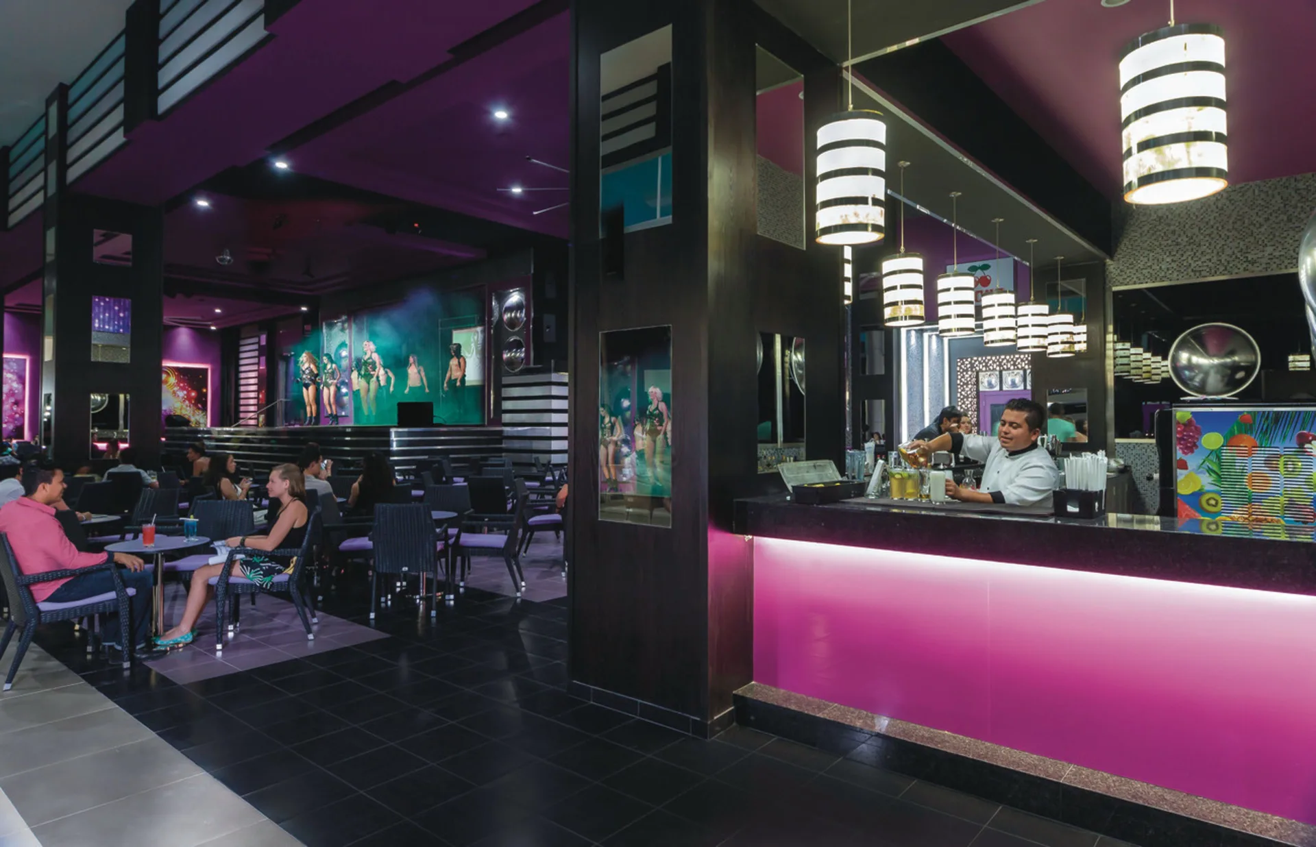 Purple bar and stage lounge with guests seated at Hotel Riu Cancun.