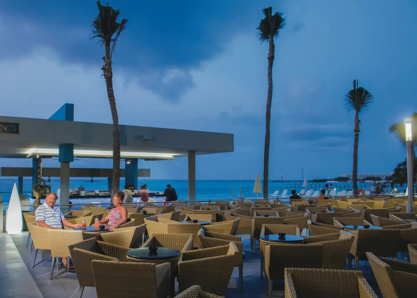 Open-air seaside bar terrace with wicker seating at Hotel Riu Cancun.