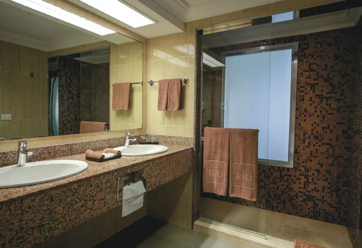 Junior Suite Ocean View bathroom with double sinks and glass shower at Hotel Riu Cancun.