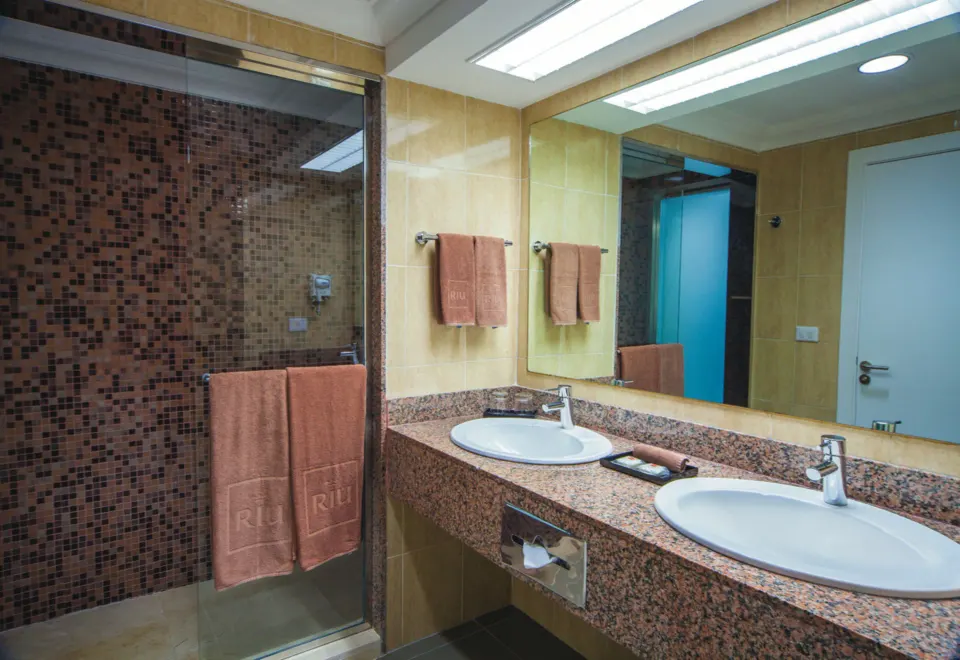 Standard Ocean View bathroom with double sinks and glass shower at Hotel Riu Cancun.