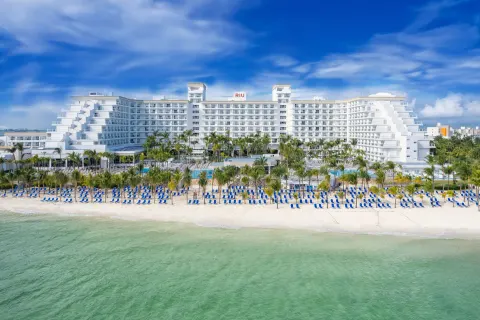 Beachfront exterior, rows of blue loungers, and turquoise water at Hotel Riu Caribe.