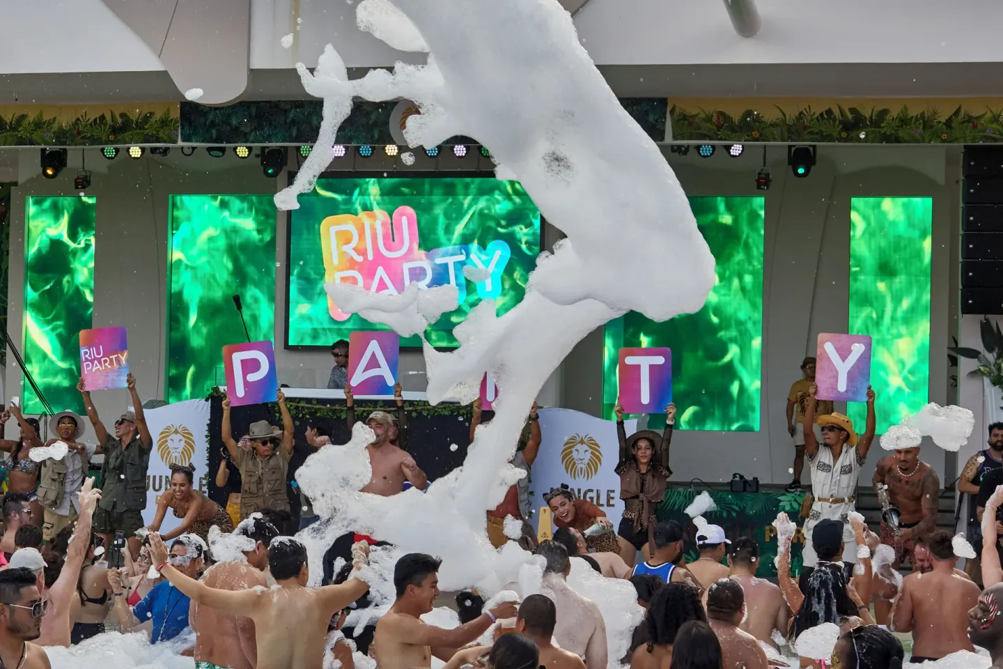 Foam party crowd in front of a stage and screens at Hotel Riu Caribe.