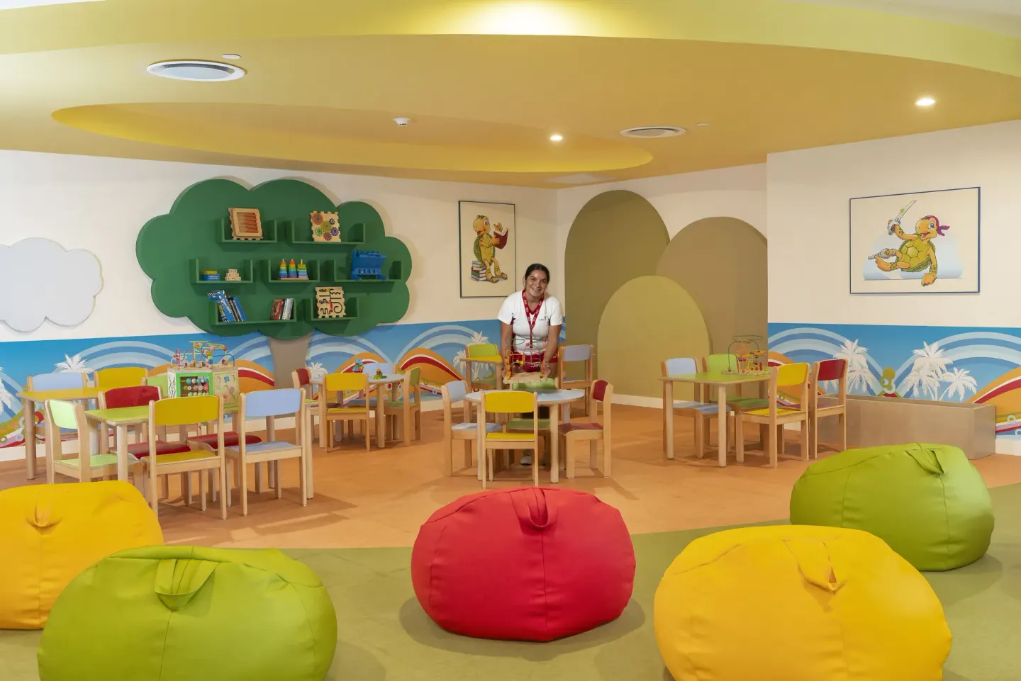 A colorful kids club playroom with tables and beanbags at Hotel Riu Caribe.