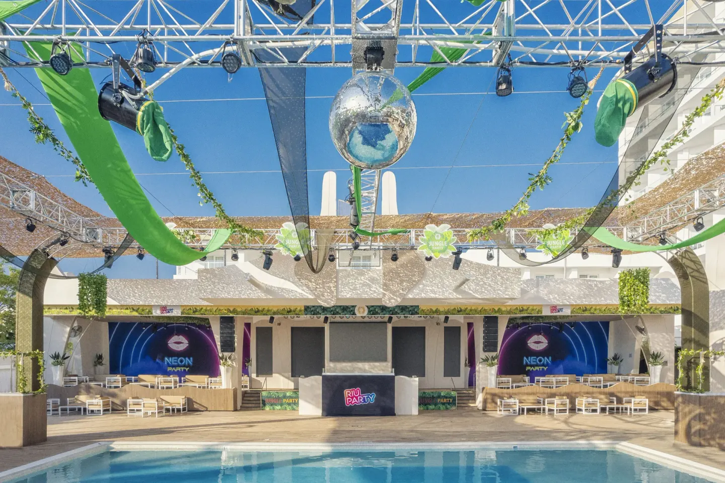 Outdoor party pool stage with lighting truss and disco ball at Hotel Riu Caribe.