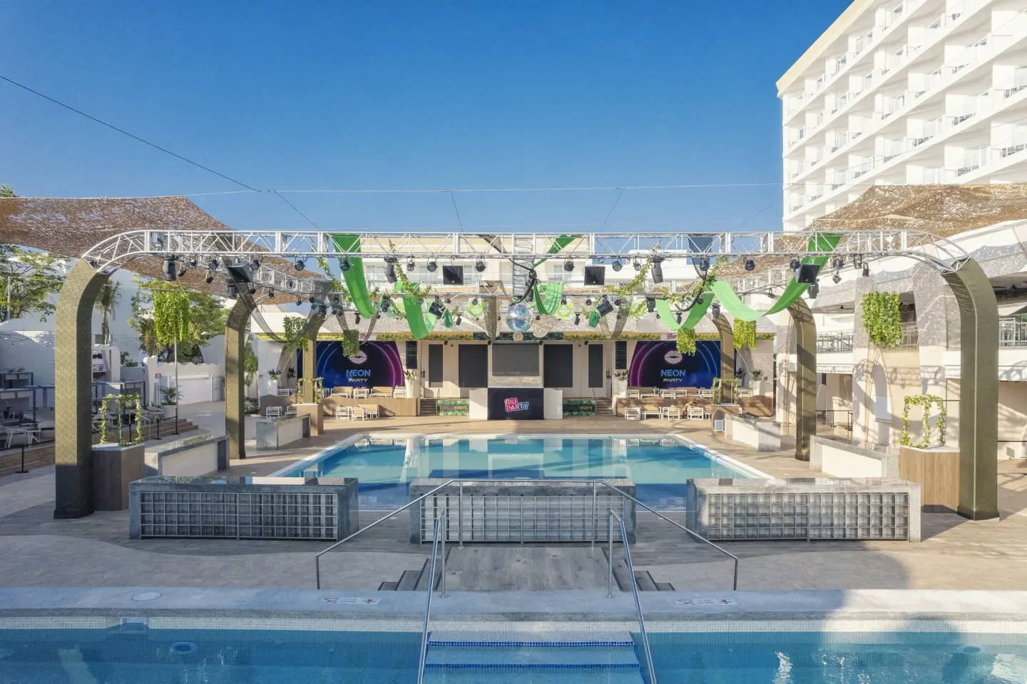 Pool and outdoor event stage with hotel balconies behind at Hotel Riu Caribe.
