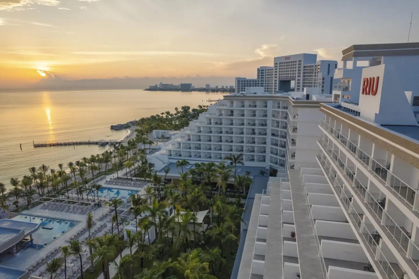 Sunset over the water beside the balconies and pools of Hotel Riu Caribe.