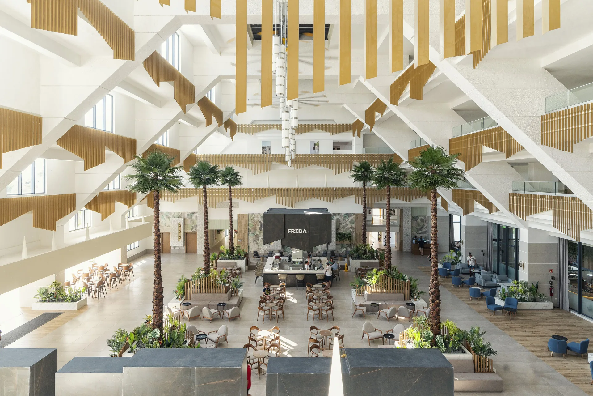 Tall atrium lobby with palms and the Frida bar sign visible at Hotel Riu Caribe.