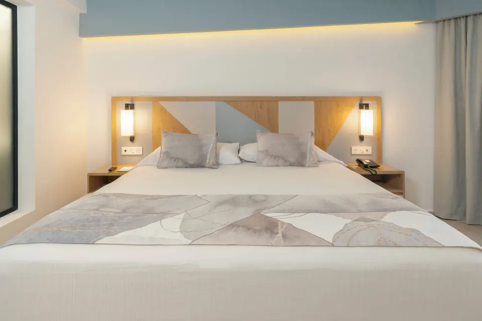 Junior Suite Oceanfront king bed with lit headboard and bedside lights at Hotel Riu Caribe.