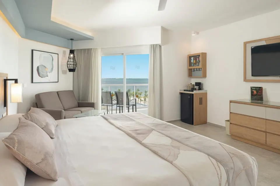 Junior Suite Oceanfront with king bed, minibar cabinet, TV, and sea view at Hotel Riu Caribe.