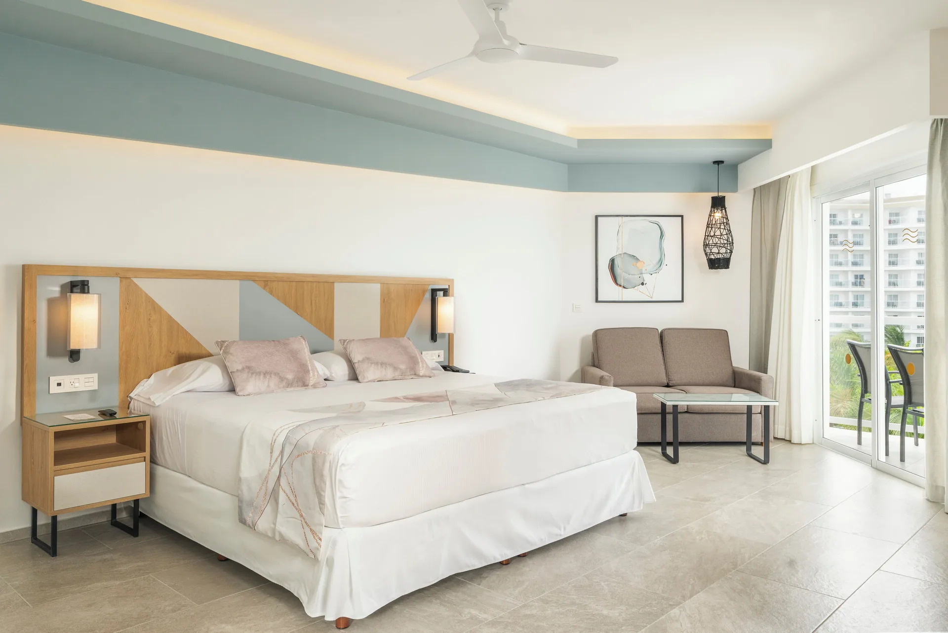 Junior Suite Oceanfront room with king bed, sofa, and balcony doors at Hotel Riu Caribe.