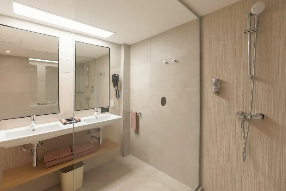 Bathroom in an Ocean View room at Hotel Riu Caribe with double sinks, mirrors, and a walk-in shower.