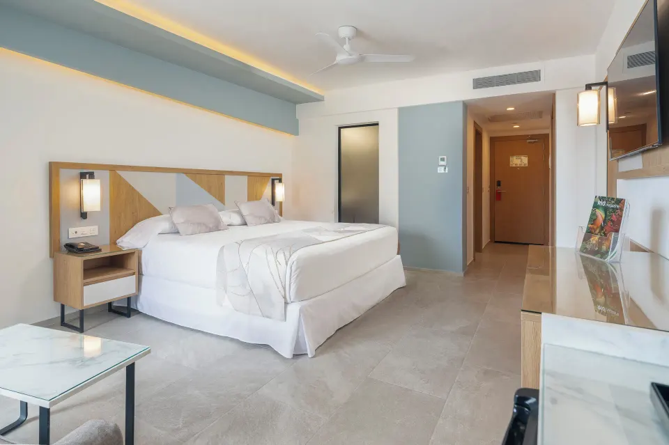 King-bed Ocean View room at Hotel Riu Caribe with a TV console, coffee table, and entry corridor.