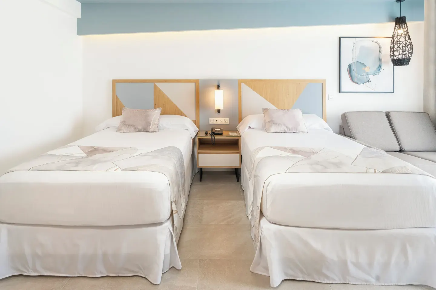 Two double beds in an Ocean View room at Hotel Riu Caribe with a sofa and wall art.