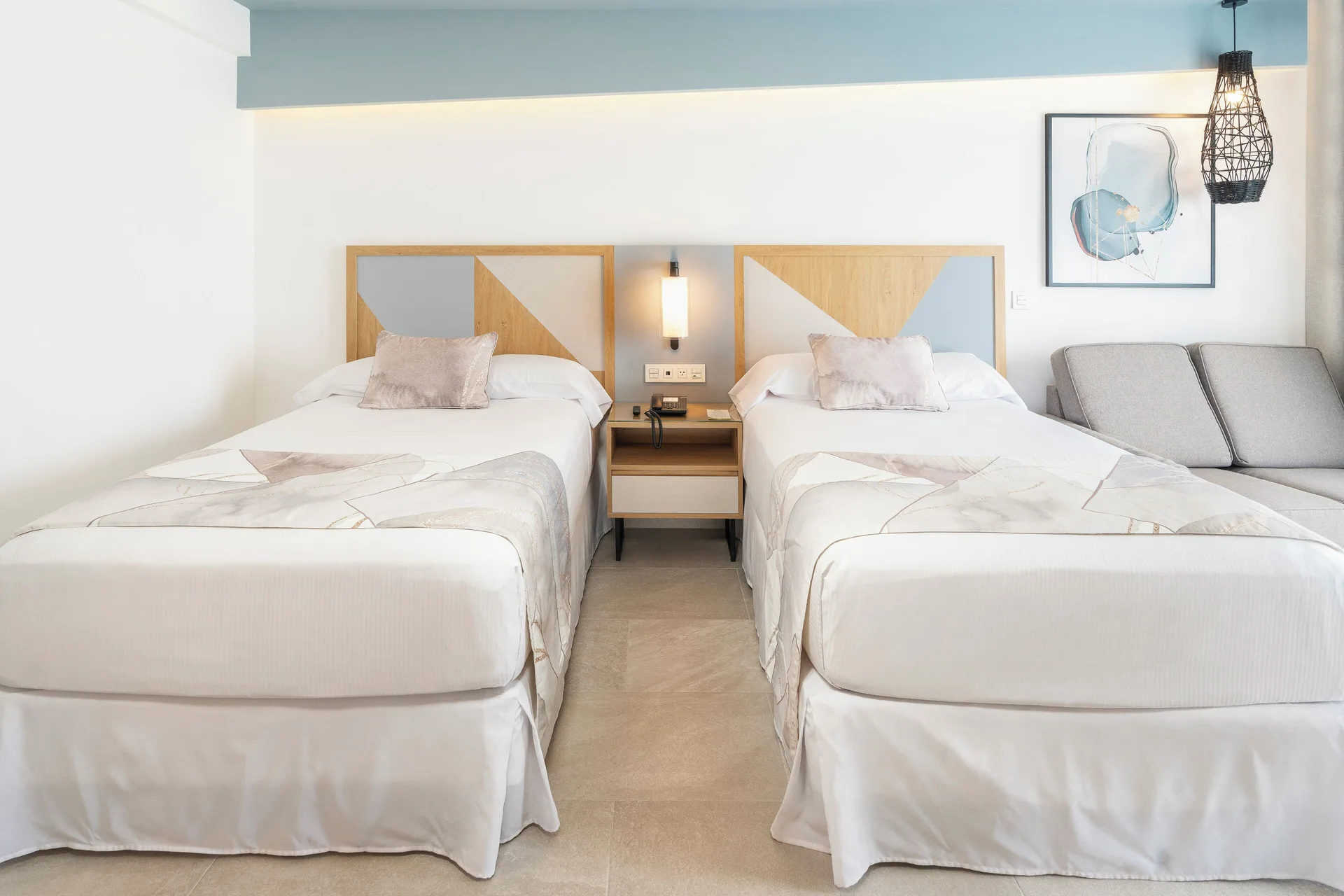 Two double beds in an Ocean View room at Hotel Riu Caribe with a sofa and wall art.