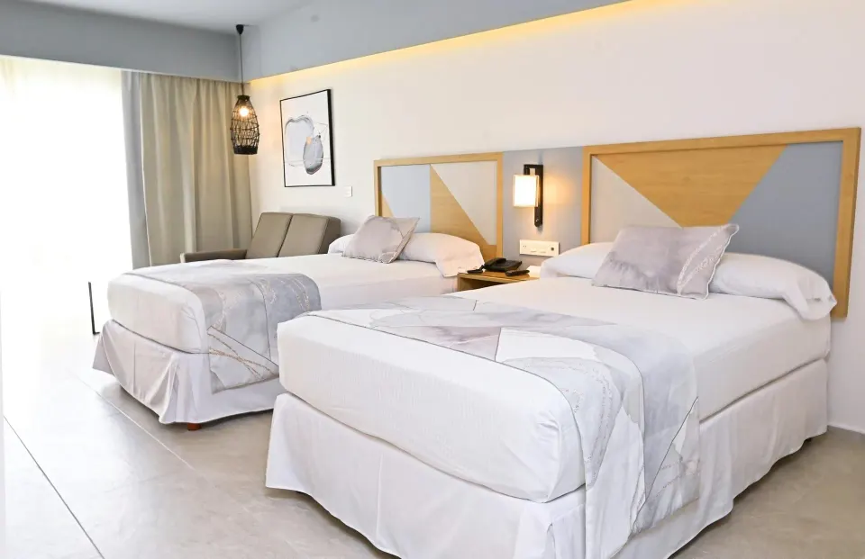 Two double beds with geometric headboards in a guest room at Hotel Riu Caribe.