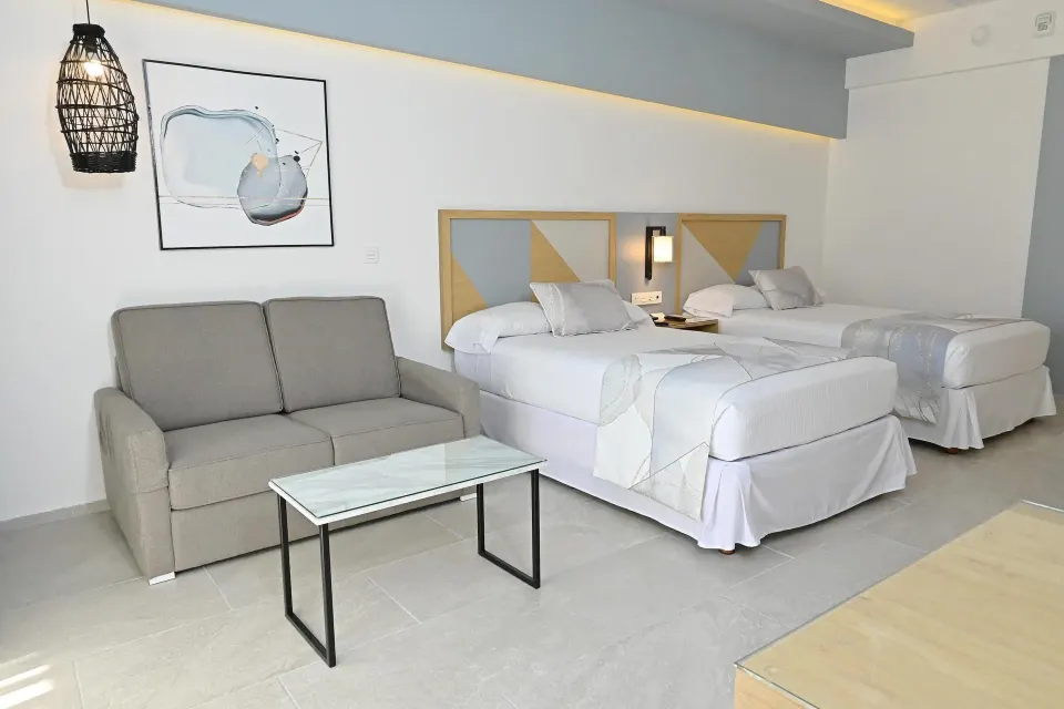 Guest room seating area beside two double beds at Hotel Riu Caribe.