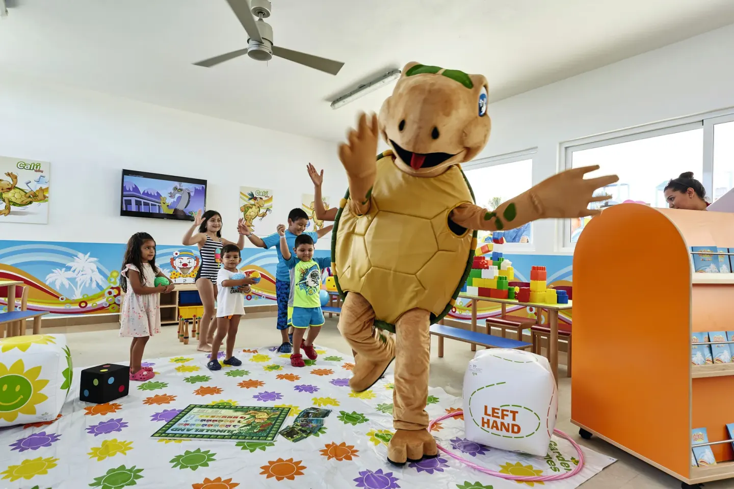 Children play with a turtle mascot in the kids club at Hotel Riu Dunamar.