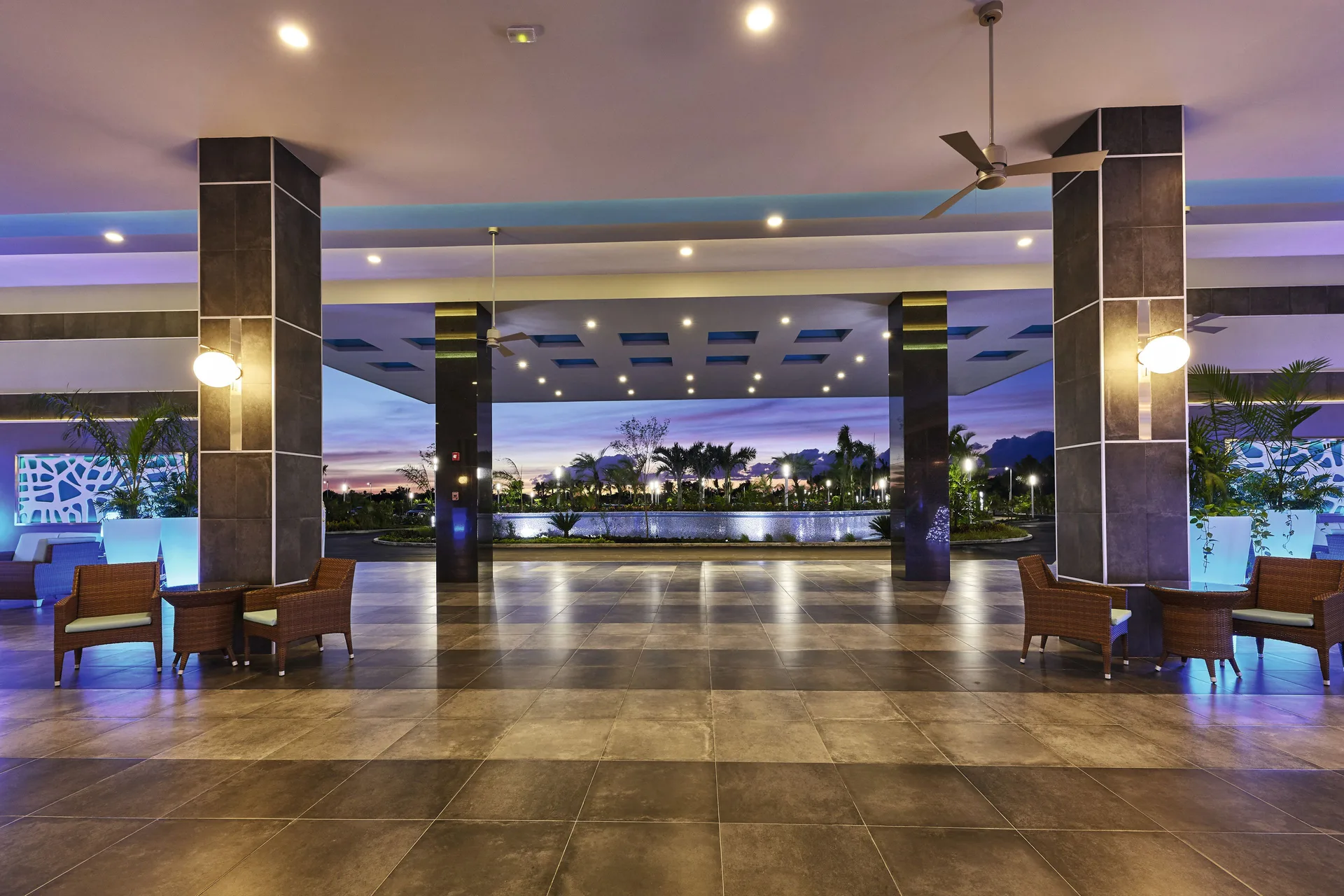 Open-air entrance area at Hotel Riu Dunamar with seating, columns, and evening lighting.