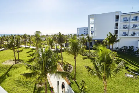 Palm-lined garden walkway beside guest room buildings at Hotel Riu Dunamar.