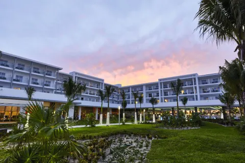 Resort courtyard with palms and guest room balconies at sunset at Hotel Riu Dunamar.