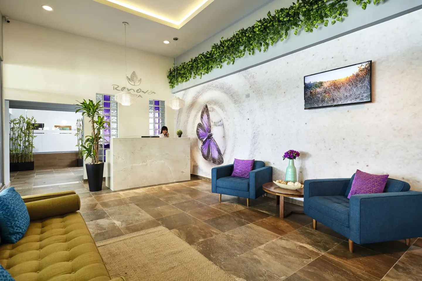 Spa reception area with blue chairs and butterfly wall art at Hotel Riu Dunamar.