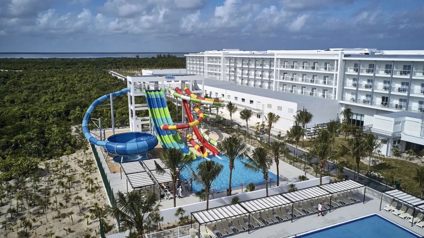 Aerial view of colorful waterslides, pools, and hotel buildings at Hotel Riu Dunamar.