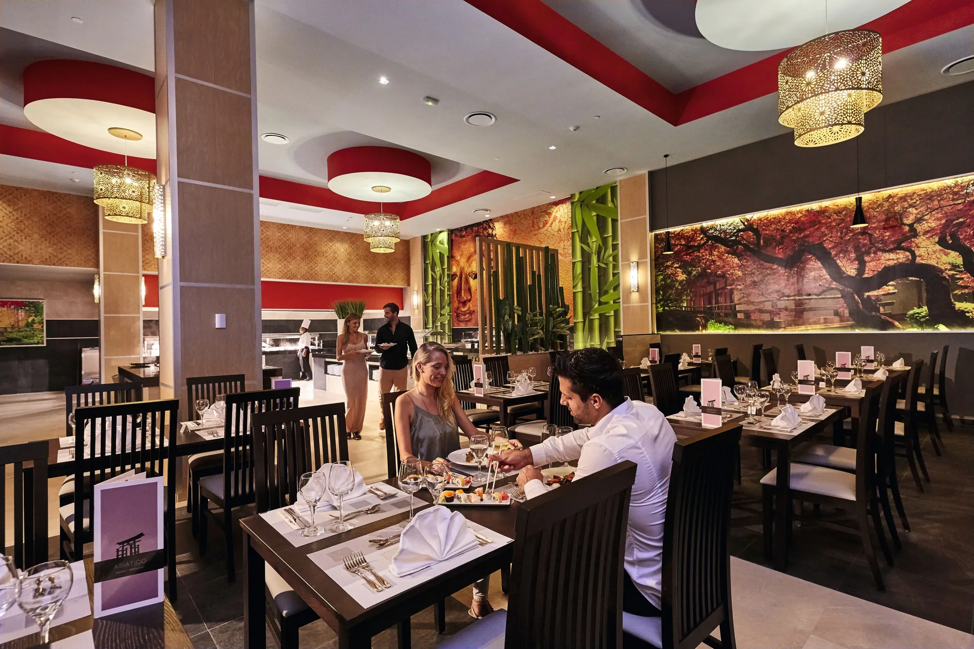 An Asian restaurant dining room with bamboo decor and set tables at Hotel Riu Dunamar.