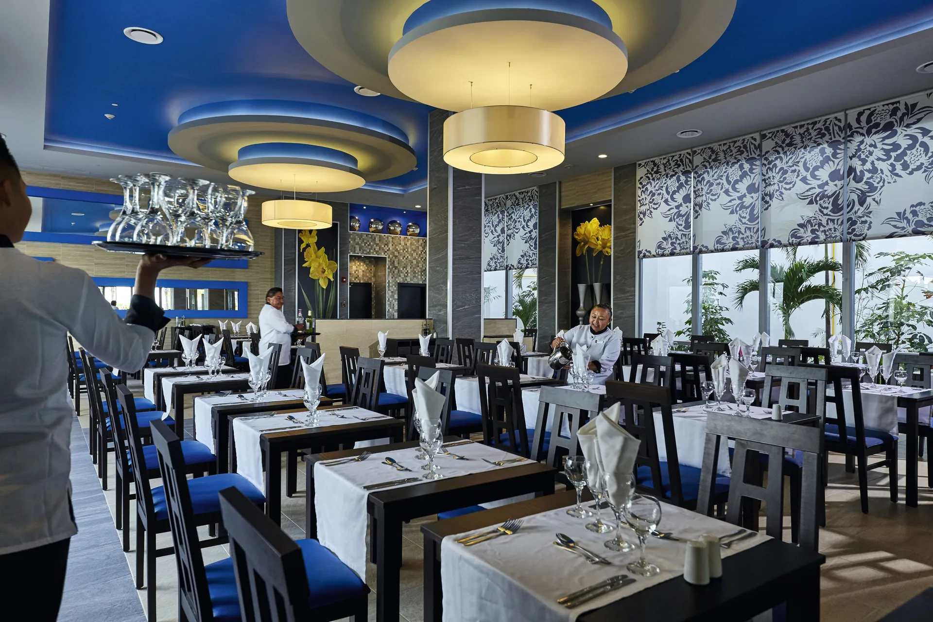 Blue-accented restaurant dining room with servers at Hotel Riu Dunamar.