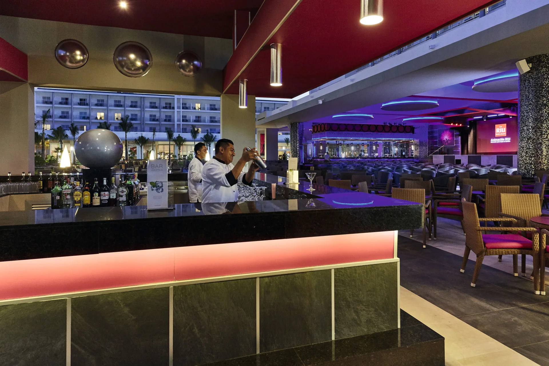 Open-air evening bar with bartenders and lounge seating at Hotel Riu Dunamar.