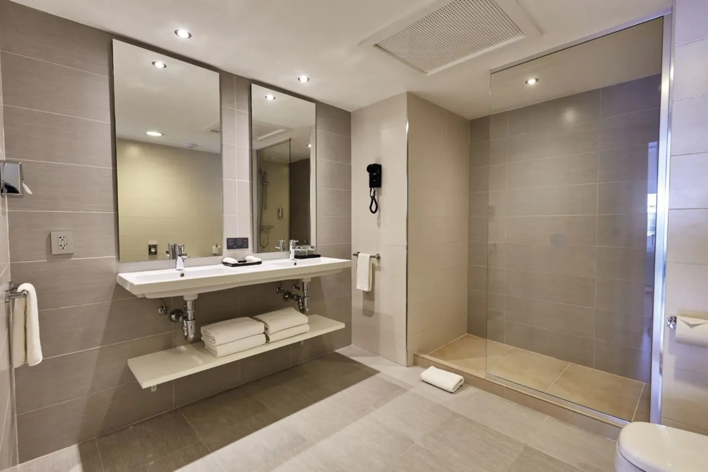 Family Suite bathroom with double sink vanity and glass shower at Hotel Riu Dunamar.