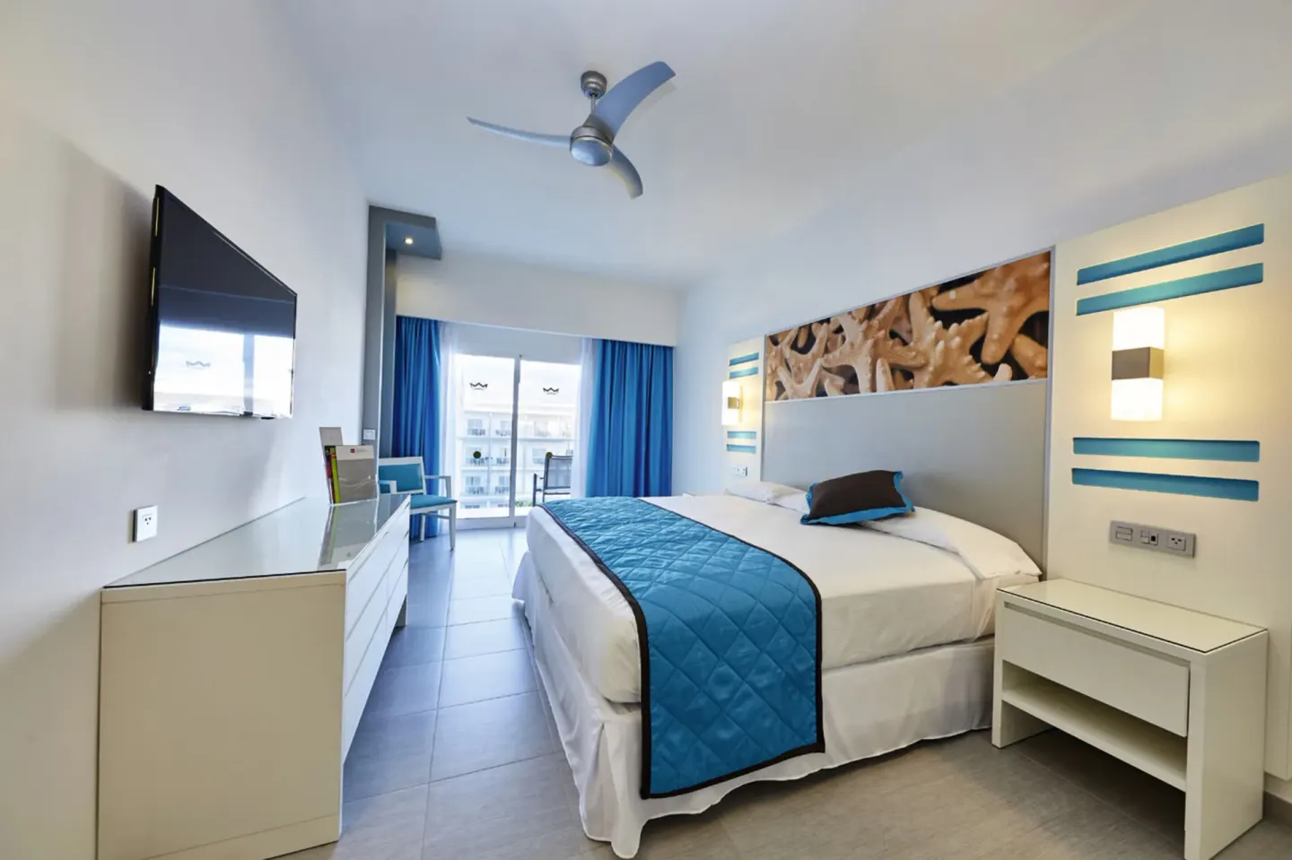 Family Suite bedroom with double bed, TV, and balcony doors at Hotel Riu Dunamar.