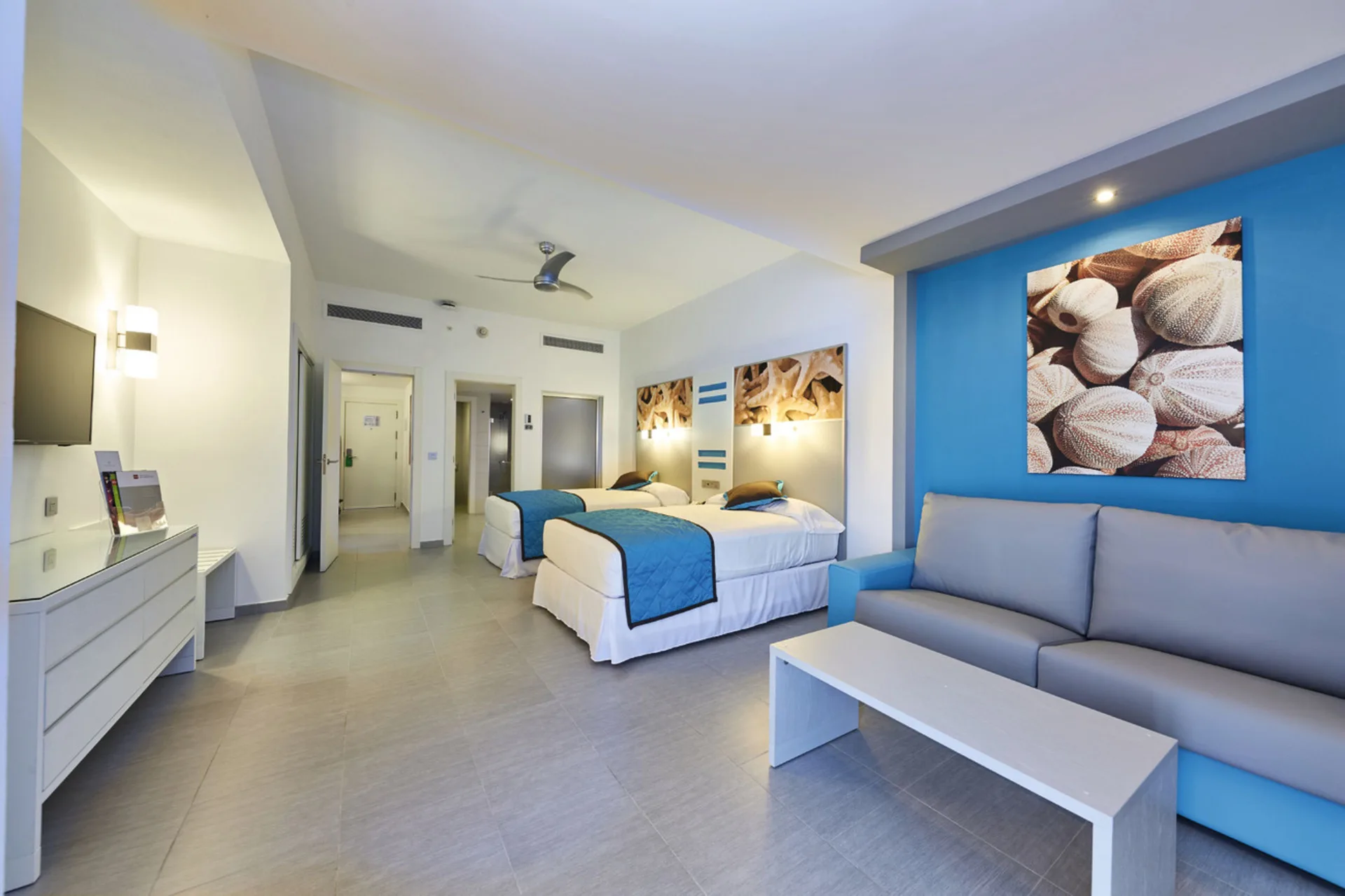 Family Suite living and bedroom area with two beds and sofa at Hotel Riu Dunamar.