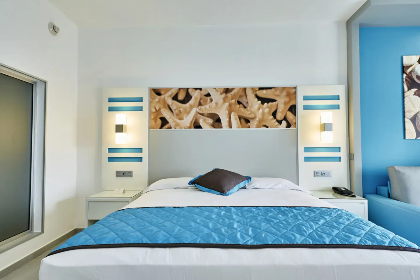 King bed with starfish headboard art in an Ocean View room at Hotel Riu Dunamar.