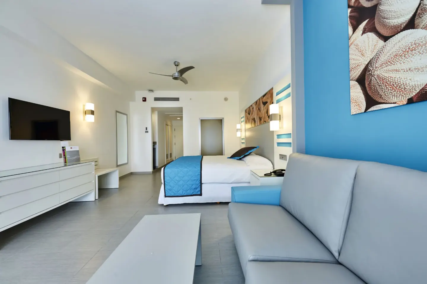 Ocean View room seating area with sofa, TV, and king bed at Hotel Riu Dunamar.