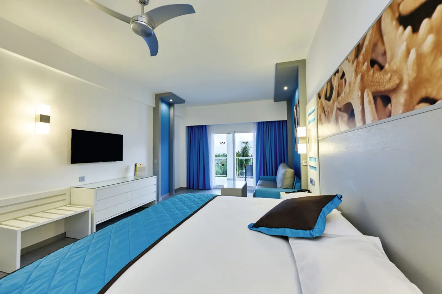 Partial Ocean View room bed facing balcony doors at Hotel Riu Dunamar.