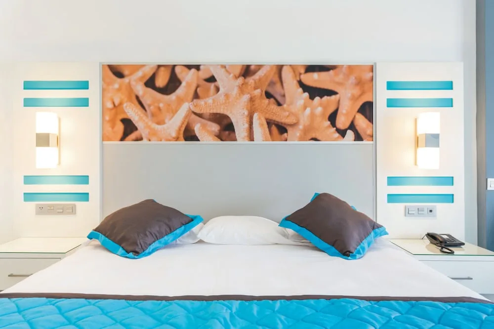 Standard room bed with starfish headboard art at Hotel Riu Dunamar.