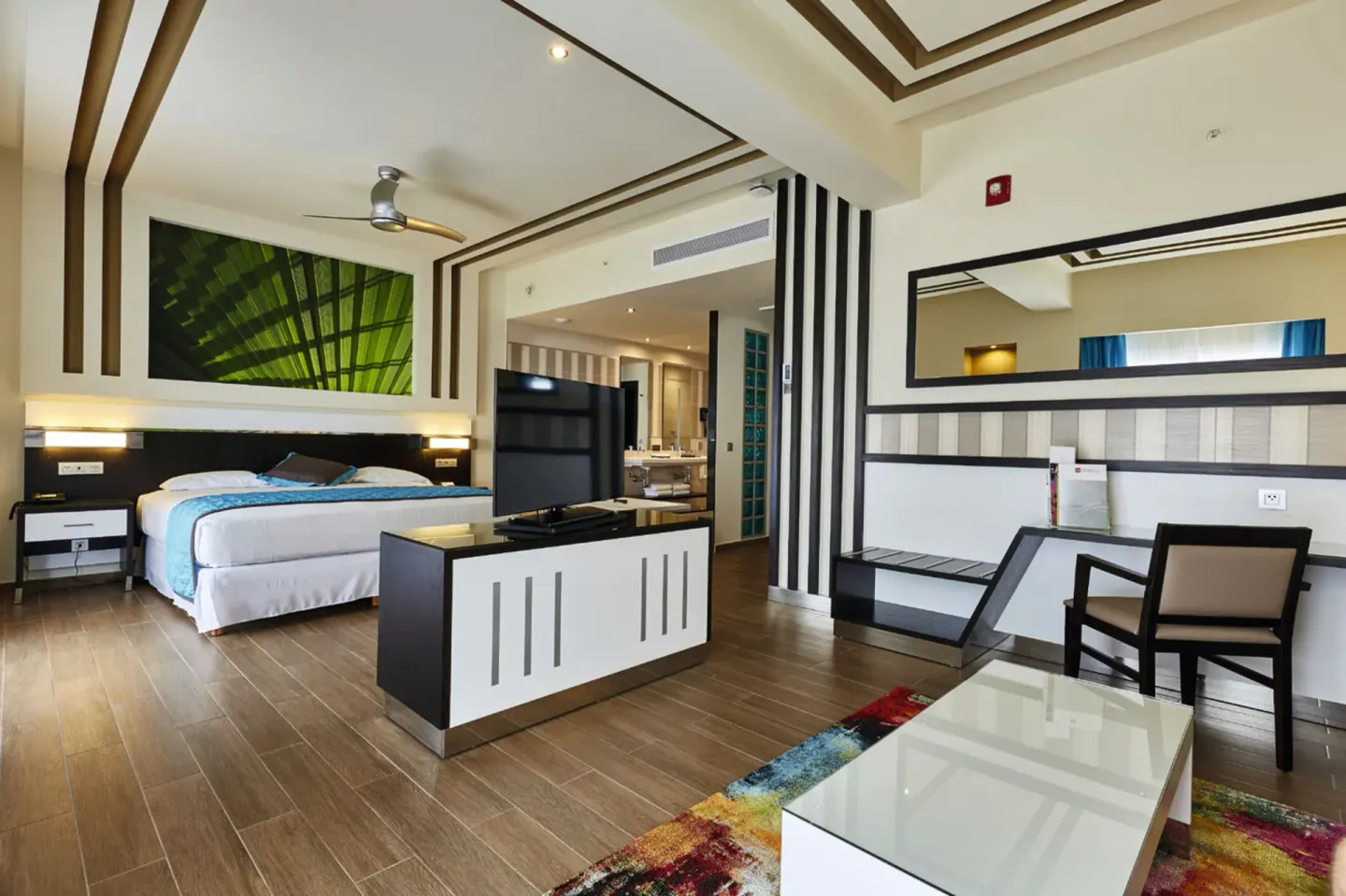 Suite sitting area and bed with TV divider at Hotel Riu Dunamar.