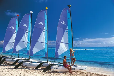 Catamarans with blue sails lined up on the beach at Hotel Riu Guanacaste.