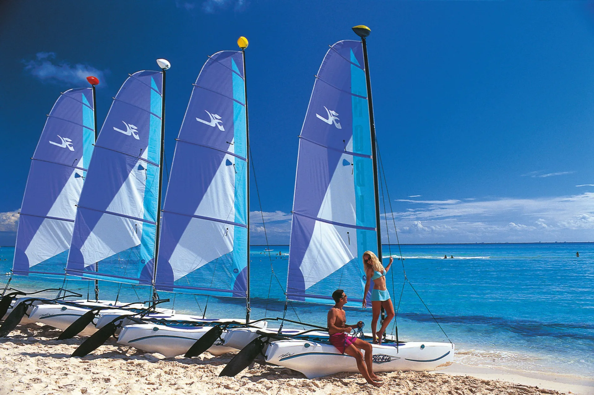 Catamarans with blue sails lined up on the beach at Hotel Riu Guanacaste.