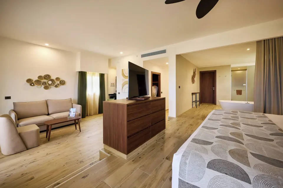 Guest room with king bed, sofa, TV, and freestanding tub at Hotel Riu Guanacaste.