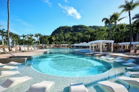 Lagoon-style pool with in-water loungers and palms at Hotel Riu Guanacaste.