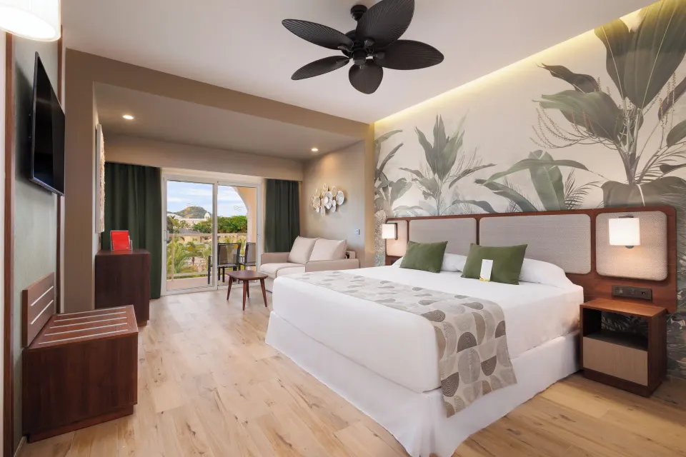 Deluxe Room Pool View with balcony doors and king bed at Hotel Riu Guanacaste.
