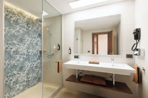 Deluxe Room bathroom with double sink and glass shower at Hotel Riu Guanacaste.