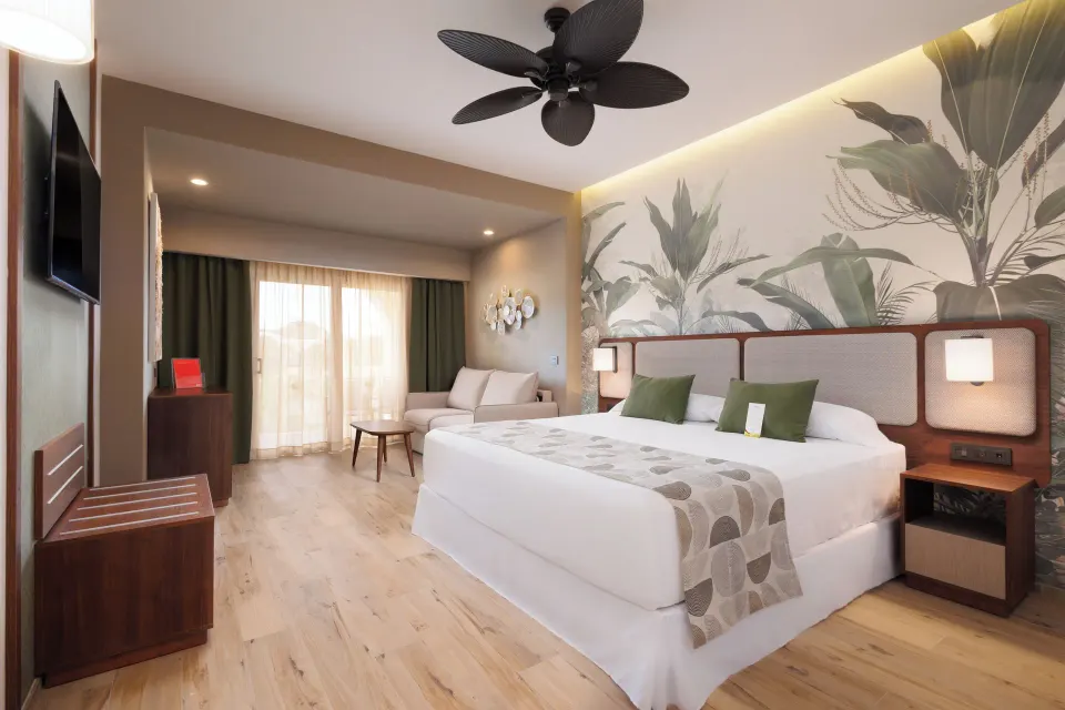 Deluxe Room with king bed, sofa and balcony doors at Hotel Riu Guanacaste.