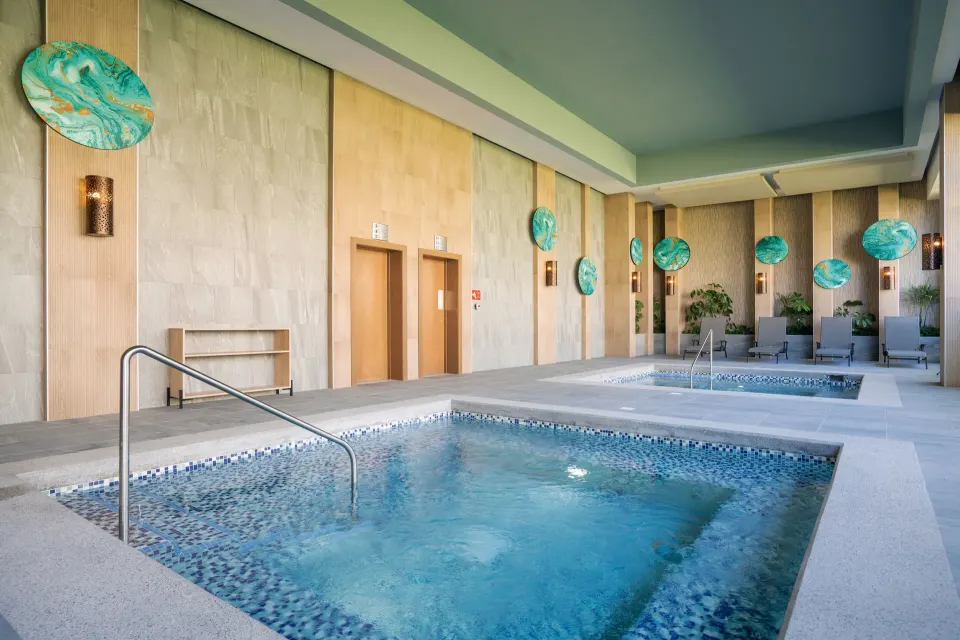 Indoor spa pools with lounge chairs and decorative walls at Hotel Riu Latino.