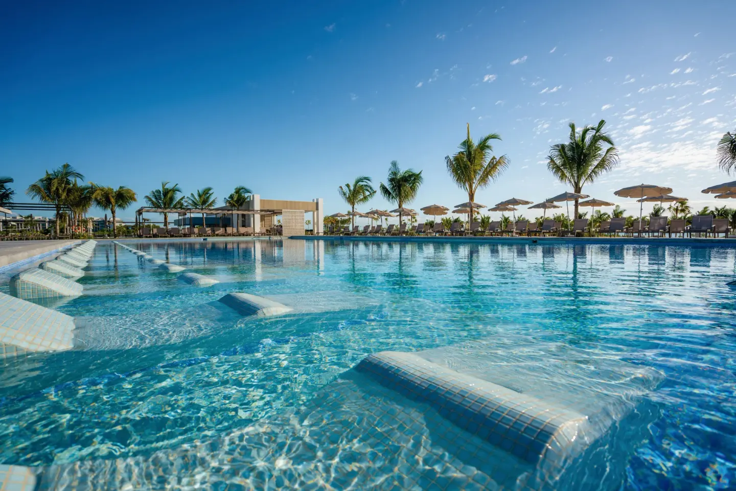 Low-angle view of submerged pool loungers and palm trees at Hotel Riu Latino.