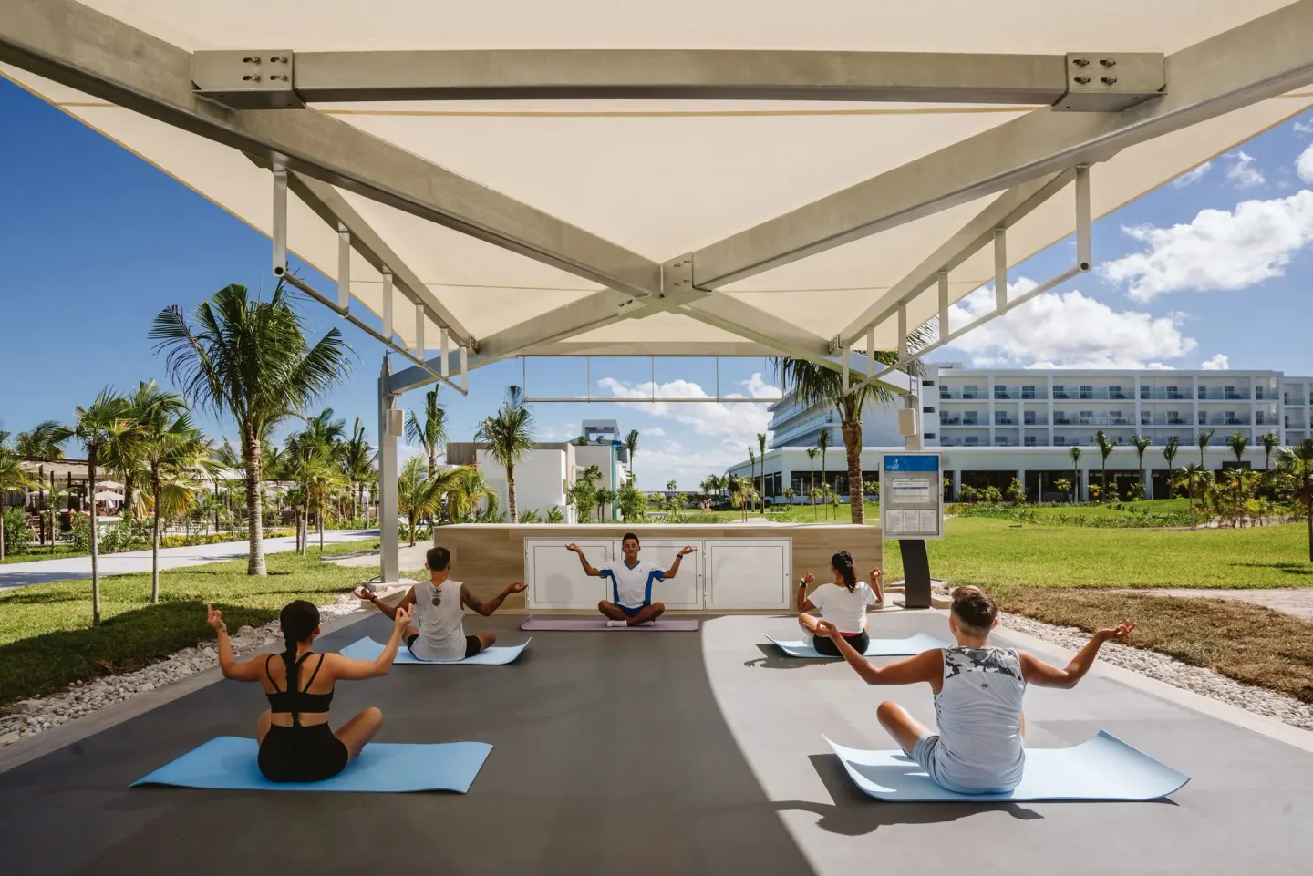 Outdoor yoga class under a shaded pavilion at Hotel Riu Latino.