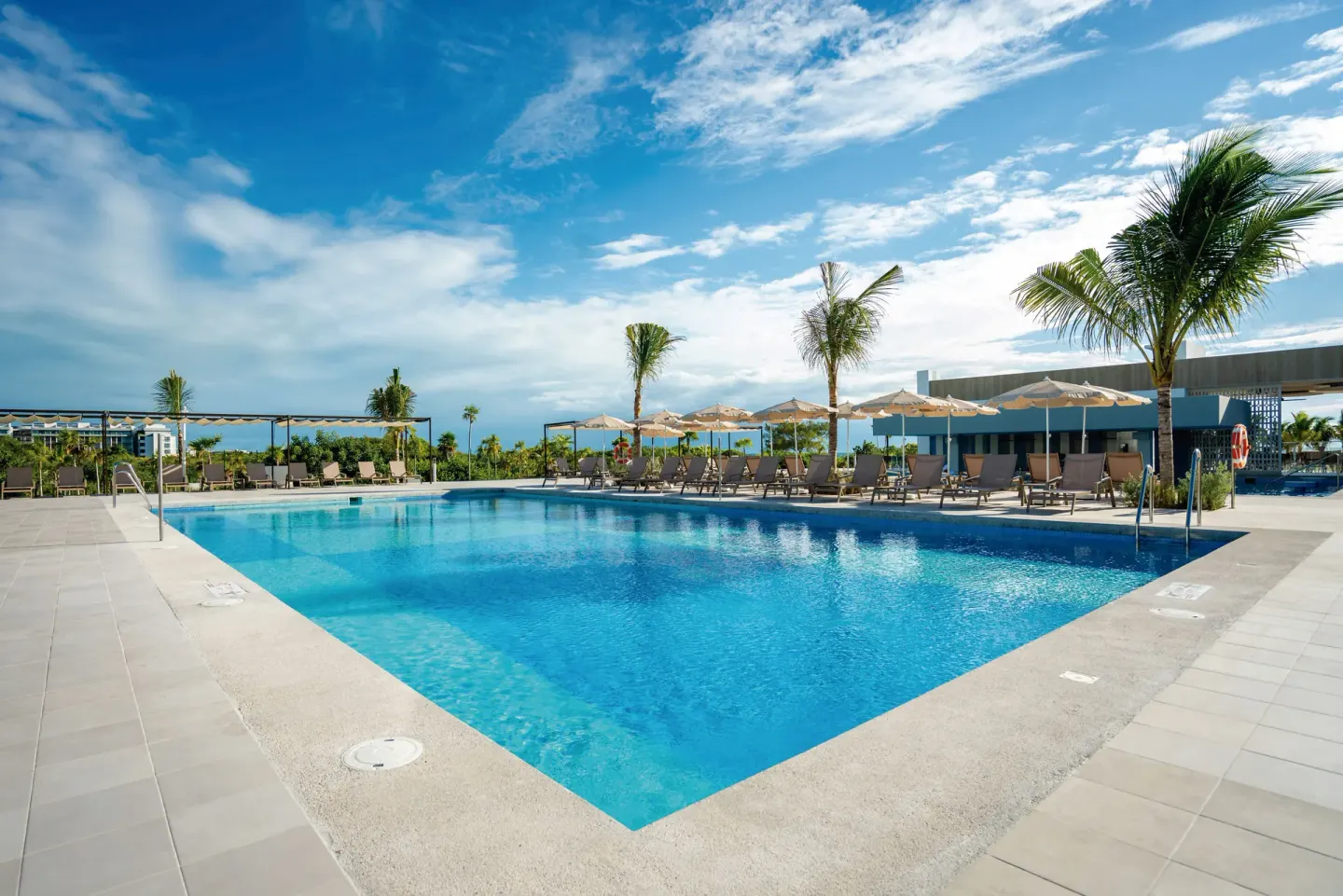 Quiet resort pool with lounge chairs, umbrellas, and palm trees at Hotel Riu Latino.